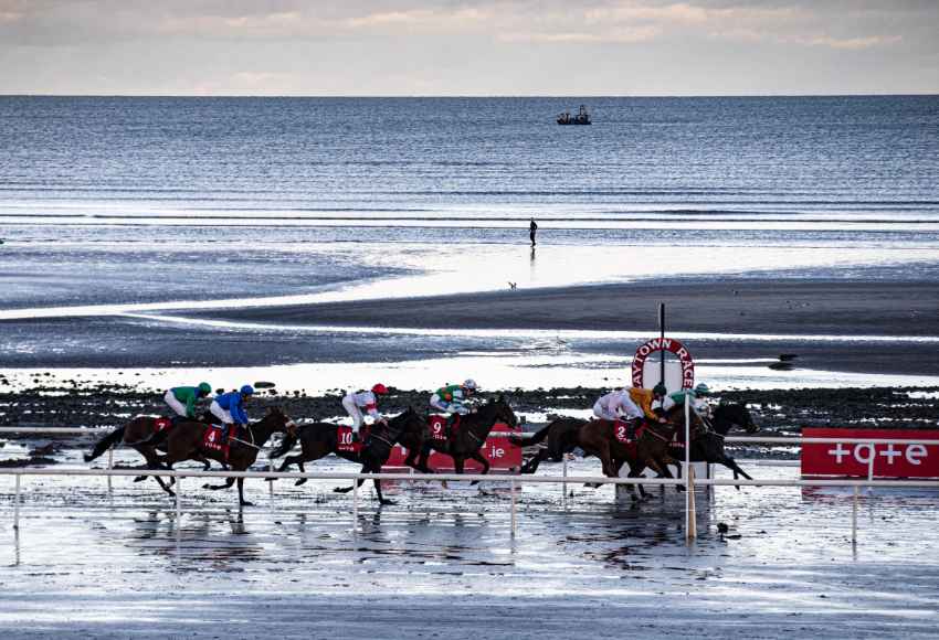 Horses running on the beach track at Laytown Racecourse with the sea in the background